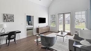 A modern hotel room with a bed, desk, chair, and a large window with blinds. - Landing | Amazing 2BD, Clubhouse, Gym (Athens)