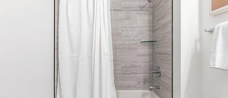 Een moderne badkamer met een douchecabine van glas, een bad en een toilet.