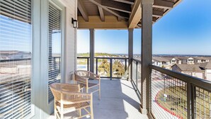 A balcony with a view of a residential area, a wicker chair, and a table. - Landing | Stunning 2BD, Pool, Clubhouse (Lakeway)