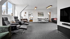 A modern, well-lit room with a large TV, comfortable seating, and a dining area. - Awesome home in Spøttrup (Spøttrup)