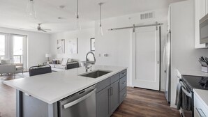 A modern kitchen with a central island, stainless steel appliances, and a sliding door closet.