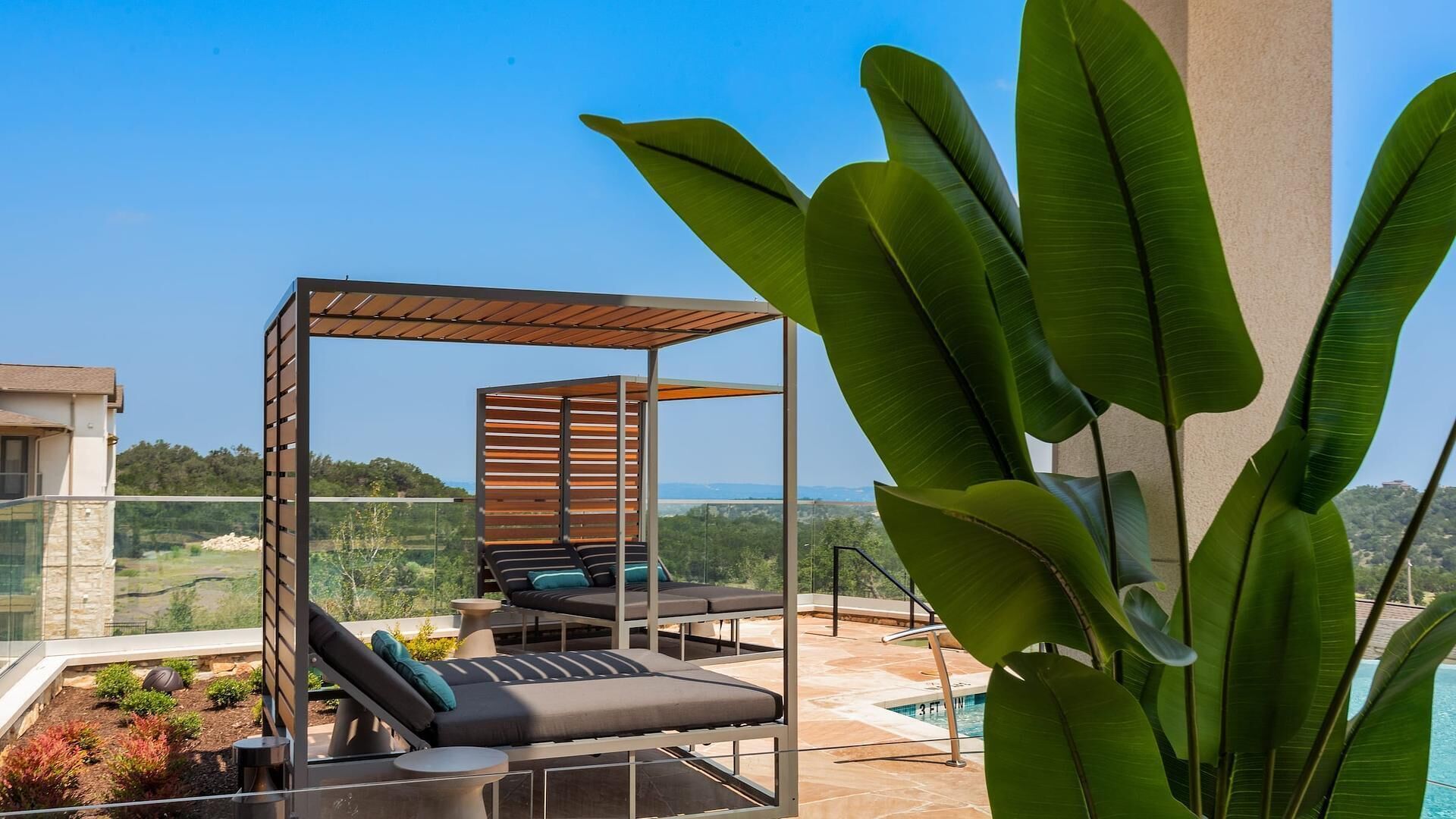 A rooftop terrace with a wooden pergola, lounge chairs, and a pool.