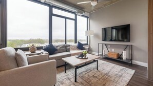 A modern living room with a sofa, coffee table, and a TV mounted on the wall.