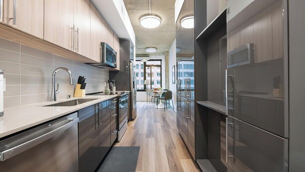 A modern kitchen with stainless steel appliances, wooden cabinets, and a central island.