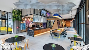 A modern interior with a central bar area, seating arrangements, and large windows providing natural light.