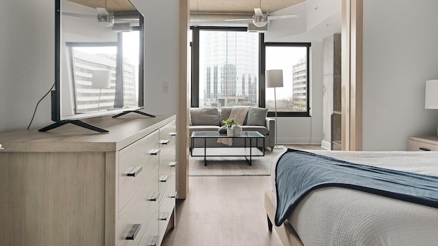 A modern hotel room with a bed, a desk with drawers, a coffee table, and a sofa.