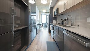 A modern kitchen with stainless steel appliances, a central island, and a view into the dining area.