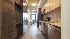 A modern kitchen with wooden cabinets, stainless steel appliances, and a central island. - Landing | Incredible 1BD, Game Room, Gym (Arlington)