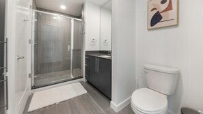 Ein modernes Badezimmer mit begehbarer Dusche, Toilette und Waschbecken.