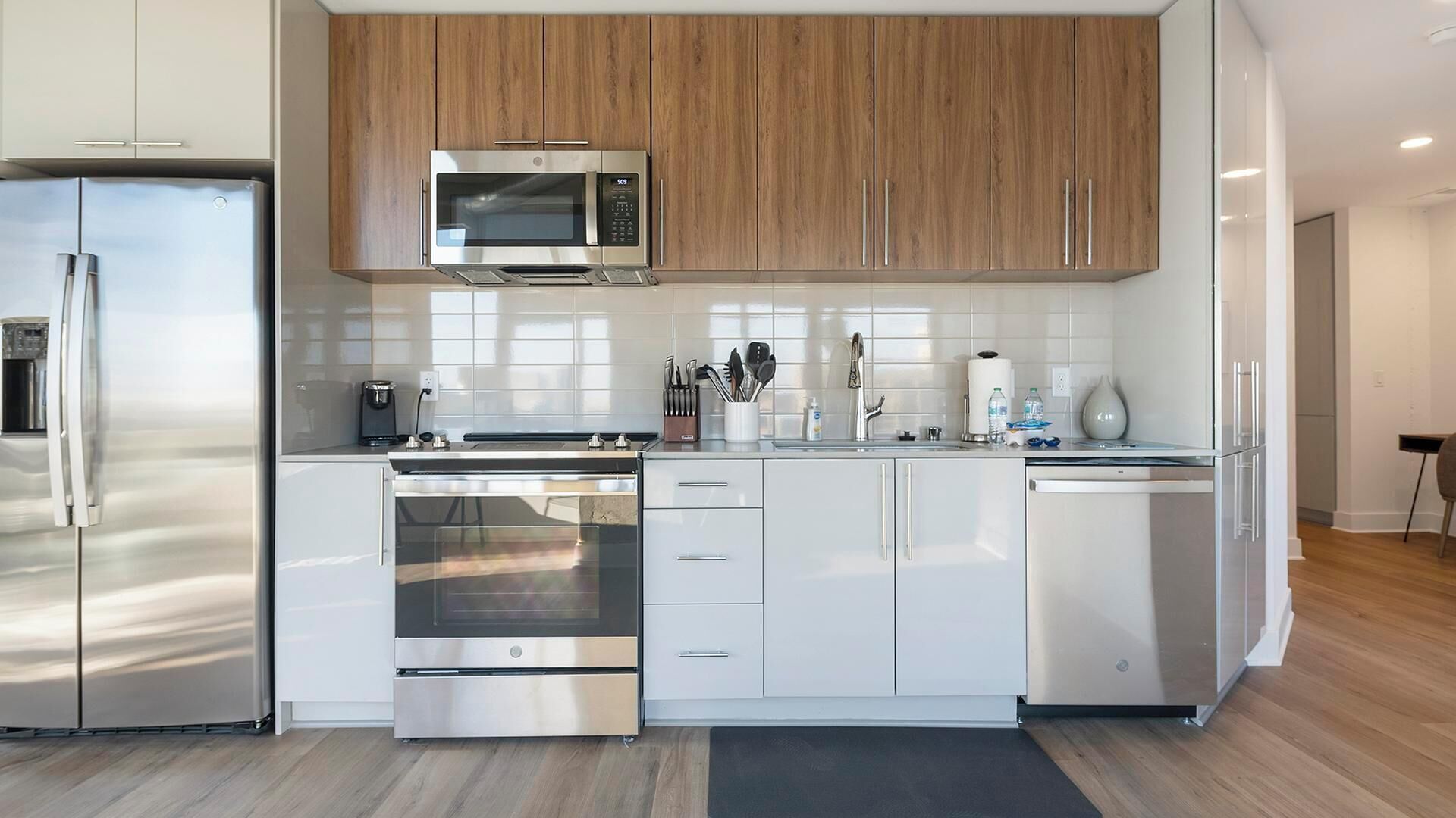 A modern kitchen with stainless steel appliances, wooden cabinets, and a tiled backsplash.