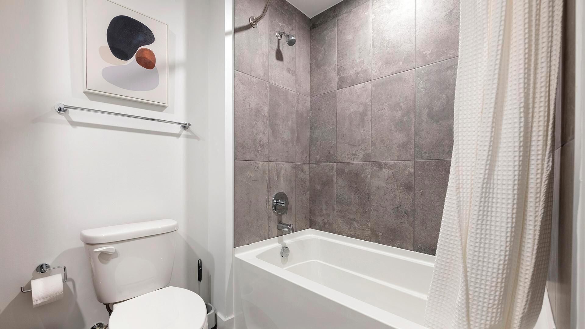 A bathroom with a bathtub, toilet, and a towel rack.