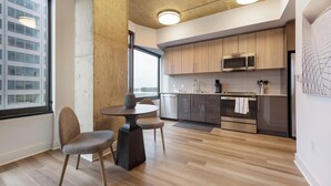 A modern kitchen with wooden cabinets, stainless steel appliances, and a dining area with a round table and chairs. - Landing | Spectacular 1BD, Gym, Game Room (Arlington)