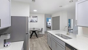 A modern kitchen with a double sink, stainless steel appliances, and a dining area with a table and chairs. - Landing | Beautiful 2BD, Clubhouse, Courtyard (Murfreesboro)