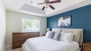 A bedroom with a bed, a dresser, a ceiling fan, a window, and a wall-mounted artwork. - Landing | Stylish 3BD, Pool (Homestead)