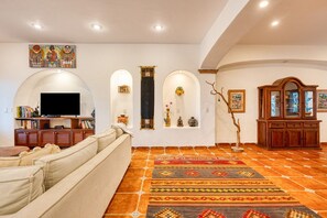Un salon comprenant un canapé, un téléviseur, des objets de décoration et un tapis à motifs.