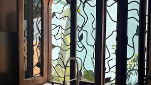 A kitchen with a sink, a bottle of dish soap, and a window with a tree pattern.