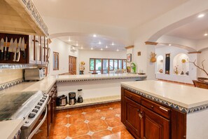 Une cuisine spacieuse dotée d’un grand îlot central, d’une cuisinière et de divers appareils électroménagers.