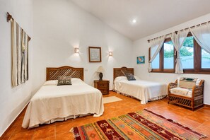 A bedroom with two beds, a nightstand, a chair, a rug, and a window with curtains. - Oceanview Getaway  Salt Pool (SAN FRANCISCO)