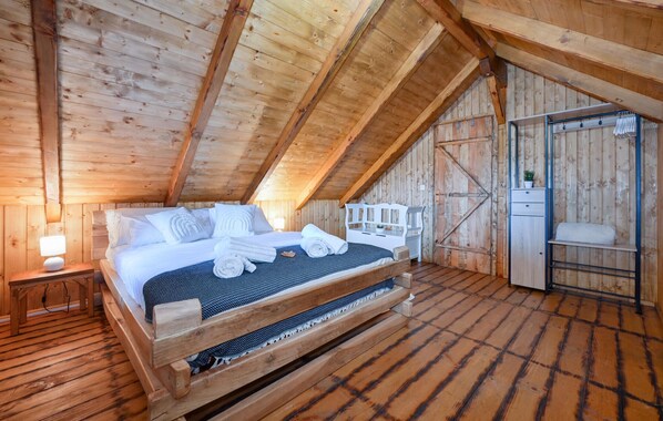 A wooden room with a bed, a nightstand, and a bench.