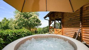 Un bain à remous avec une terrasse en bois et une vue sur une zone boisée.