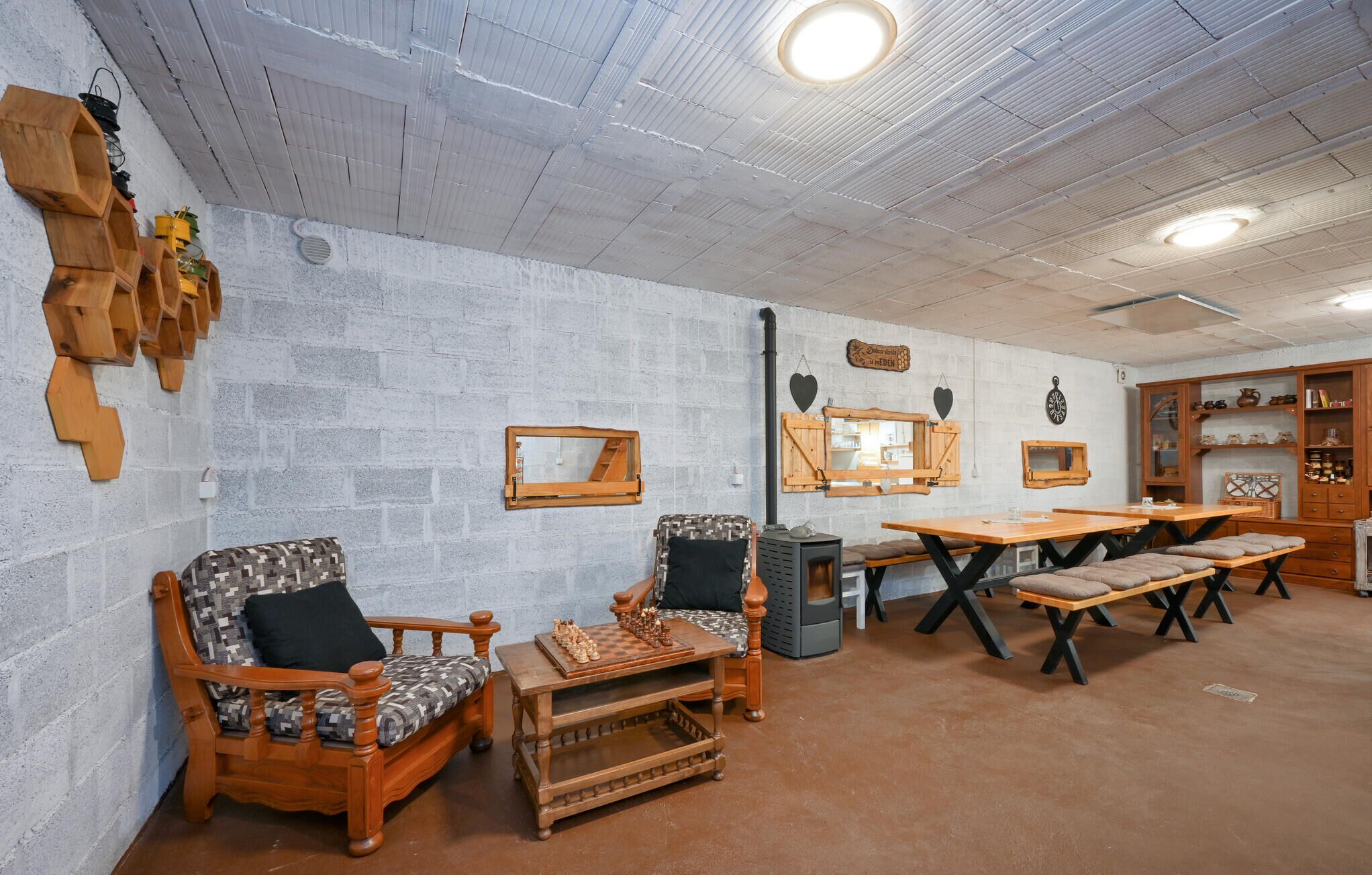 A cozy room with a wooden sofa, a chess table, and a rustic wall with wooden shelves.