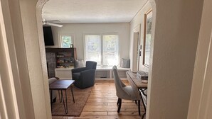 Un pasillo con piso de madera que conduce a una sala de estar con un sofá, una mesa y una silla.