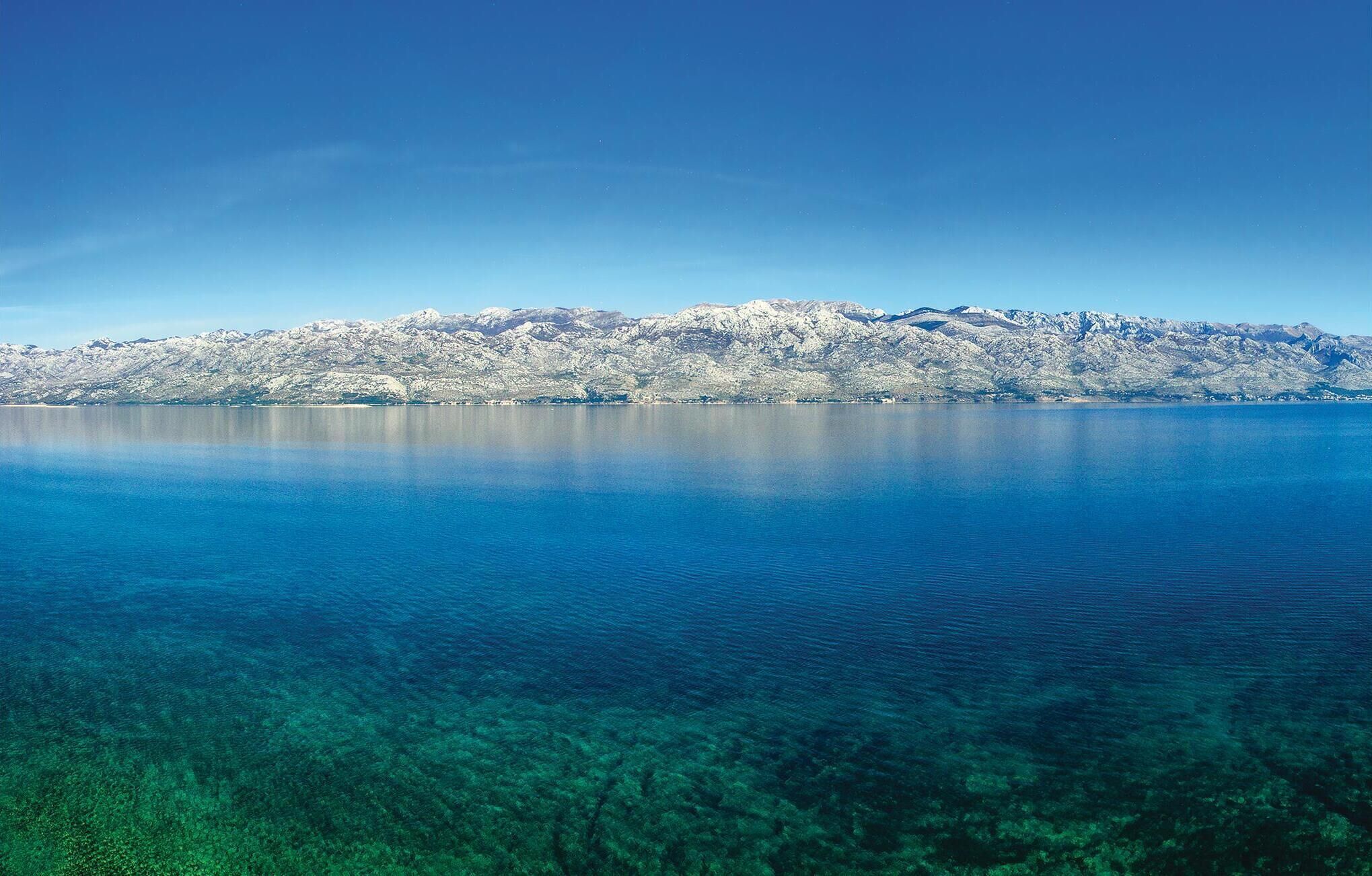 A clear view of a lake with a mountain range in the background.