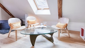 A modern loft with a glass table, two chairs, and a skylight.