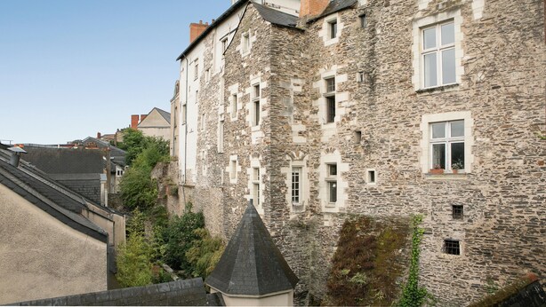 A historic stone building with multiple windows and a steeply pitched roof.