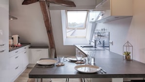 A modern kitchen with a skylight, white cabinets, and a dark countertop.