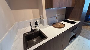 A modern kitchen with a black sink, a wine bottle, and glasses on the counter.