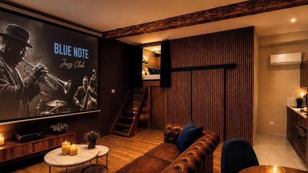 Ein modernes Wohnzimmer mit einem großen Bildschirm, der 'BLUE NOTE Jazz Club' zeigt, einer braunen Ledersofa, einem kleinen runden Tisch mit Kerzen und einer Holztreppe.