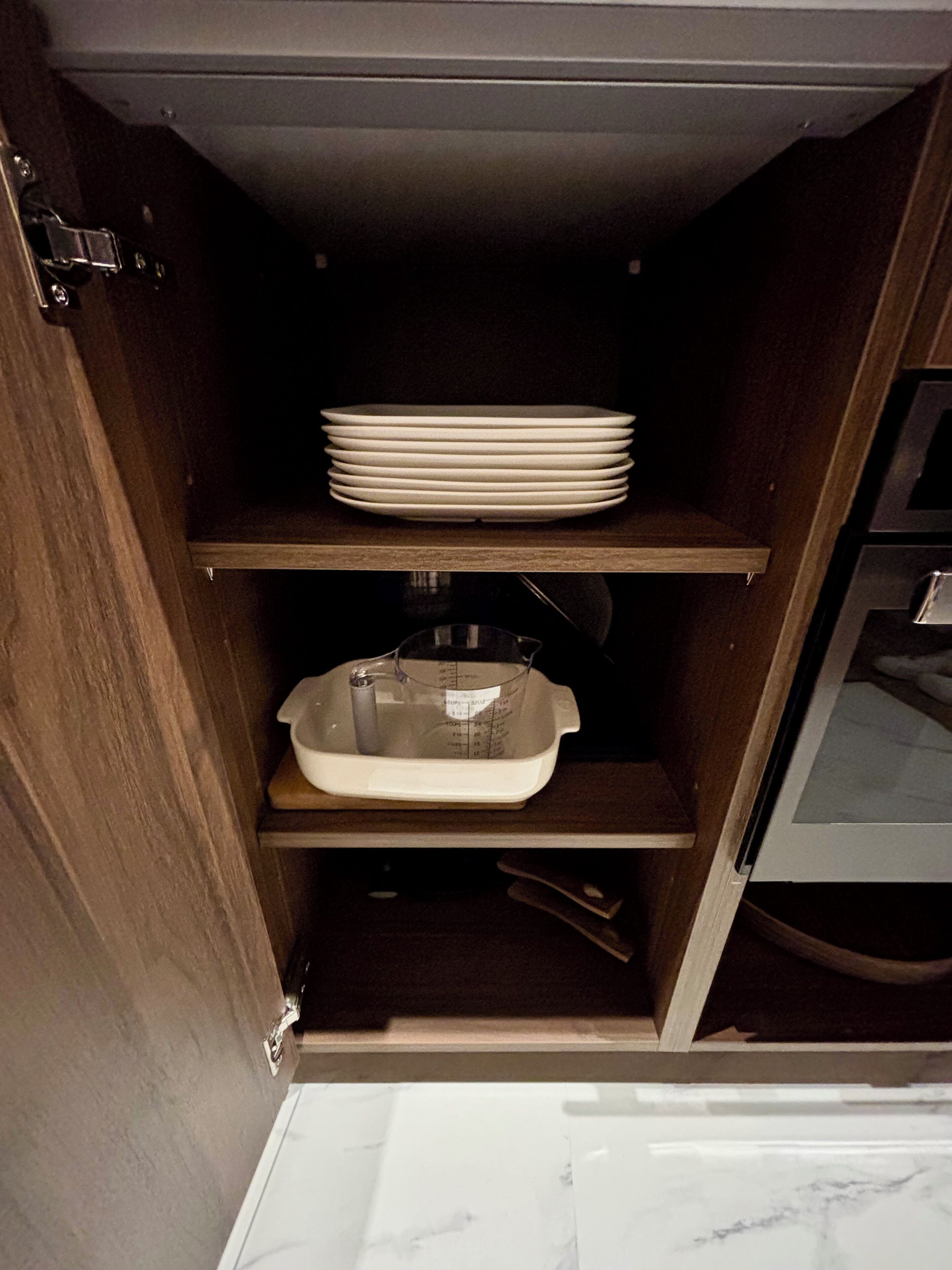 Une cuisine avec des étagères en bois, un évier et une pile d’assiettes blanches.