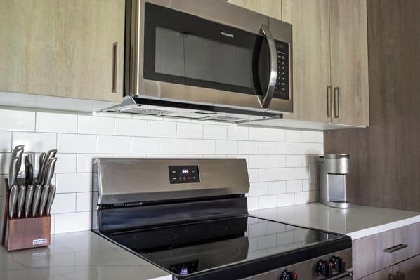 A modern kitchen with stainless steel appliances, including a microwave and oven, and a coffee maker.