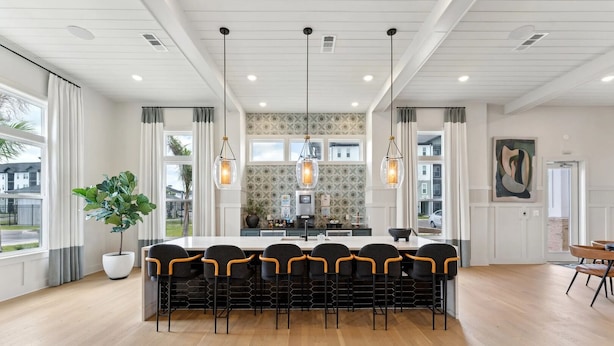Una cocina moderna con una isla central, iluminación colgante y vistas al exterior.