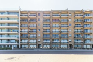 A multi-story residential building with balconies, a flat facade, and a central entrance.