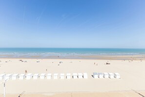 A beach with white beach huts in the foreground and a clear blue sky. - Melbourne 05.03 + G* (Sint Idesbald)