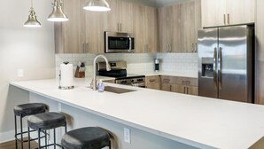 A modern kitchen with a large island, stainless steel appliances, and pendant lighting. - Landing | Amazing 1BD, Pool, Clubhouse (Fort Myers)