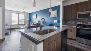 A modern kitchen with granite countertops, stainless steel appliances, and wooden cabinets. - Landing | Incredible 1BD, Gym (Houston)