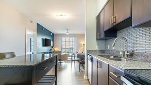 A modern kitchen with granite countertops, dark cabinetry, and a brick backsplash.