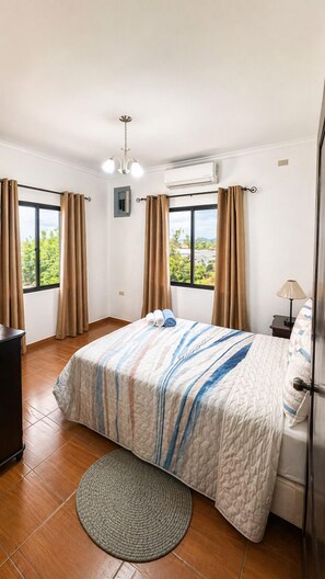A hotel room with a bed, a desk, an air conditioner, and a view of greenery. - CasaBlanca Trujillo (Trujillo)