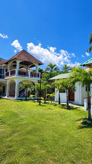 A two-story building with a balcony, surrounded by a well-maintained lawn and palm trees. - CasaBlanca Trujillo (Trujillo)