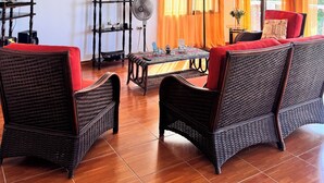 Un salon avec des meubles en osier, un téléviseur, un ventilateur et un lustre.