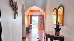 Un couloir avec un petit chien, une table en bois avec une plante et un miroir au mur.