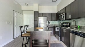 A modern kitchen with dark cabinets, stainless steel appliances, and a granite countertop.