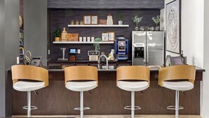 A modern kitchen with a bar area, stainless steel appliances, and wooden bar stools.