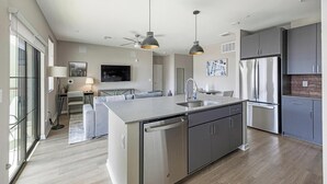 Una cocina moderna con una isla central, electrodomésticos de acero inoxidable y un área de comedor con sofá y mesa.