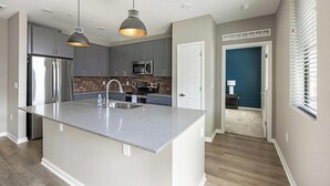 Una cocina moderna con gabinetes grises, electrodomésticos de acero inoxidable y una isla central con pileta.