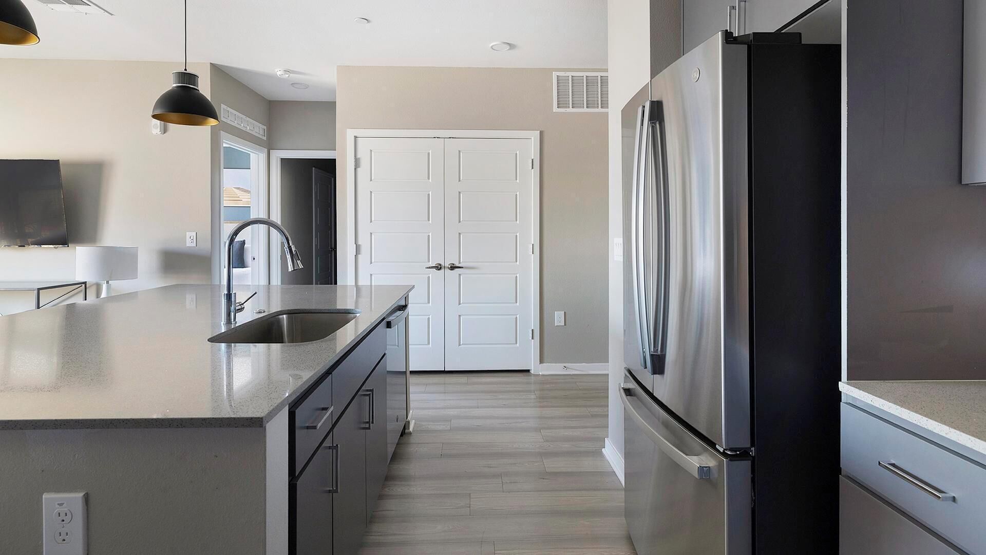 A modern kitchen with a stainless steel refrigerator, a double door white cabinet, and a countertop sink.