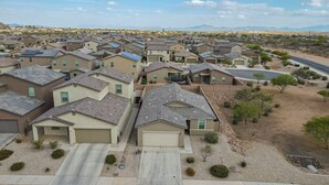 Un quartier résidentiel avec des maisons aux façades uniformes, un ciel dégagé et des montagnes à l’horizon.